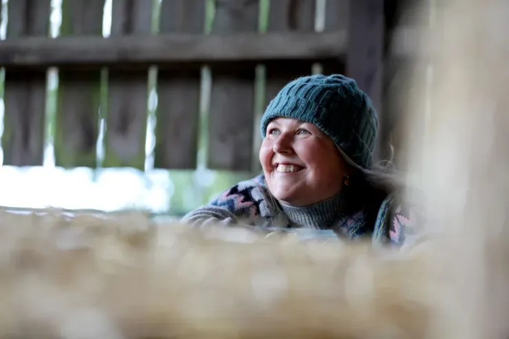 Jo Speed in a barn, leaning on a straw bale