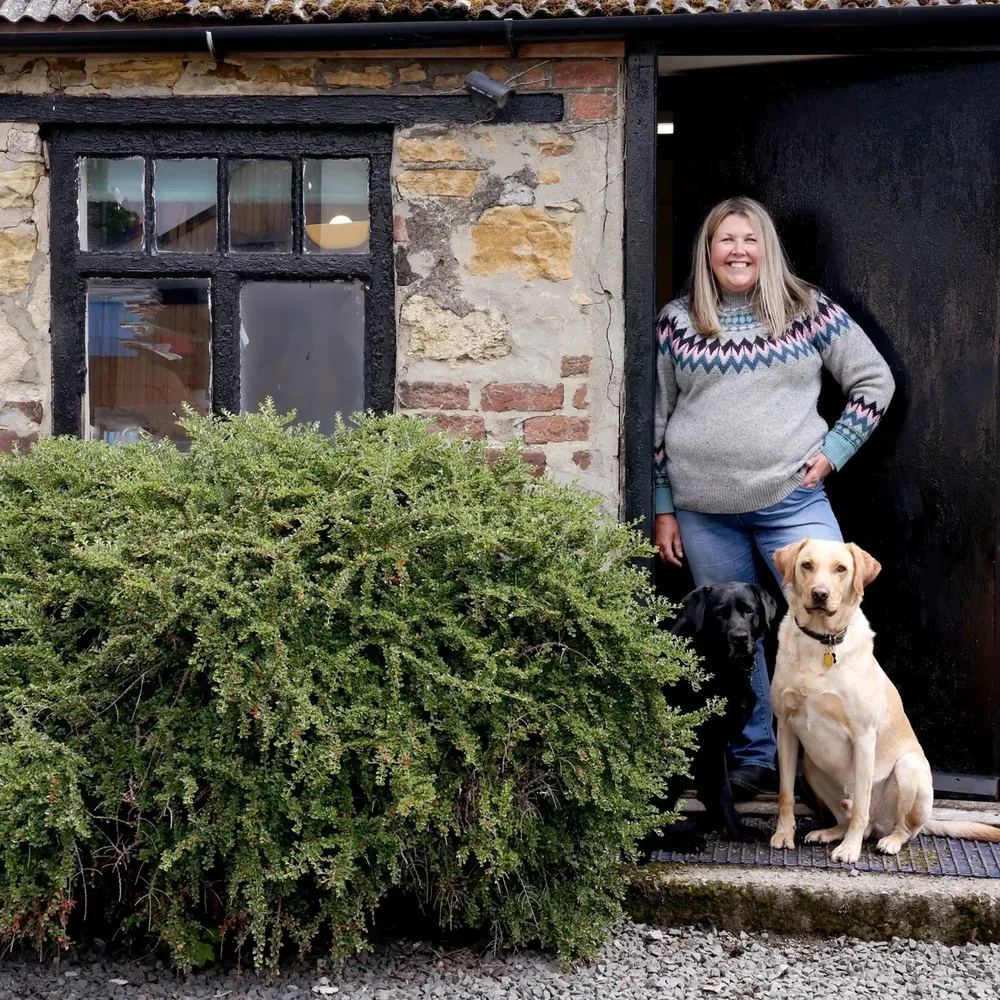 Jo Speed at the farmhouse door with her two Labradors