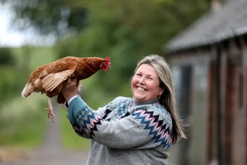 Jo Speed laughing while holding one of her rescue hens