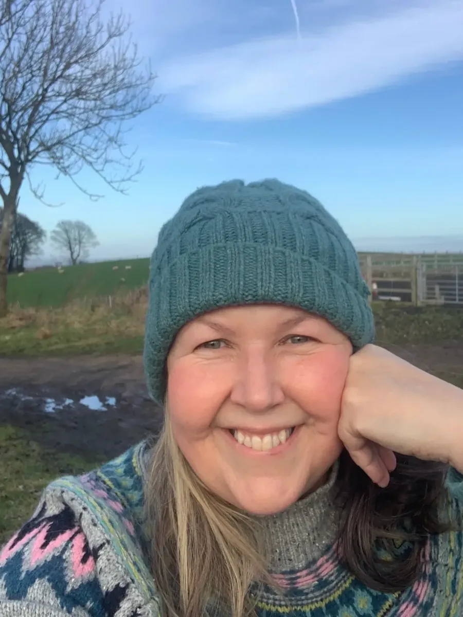 Jo Speed on her farm with sheep grazing in the field behind
